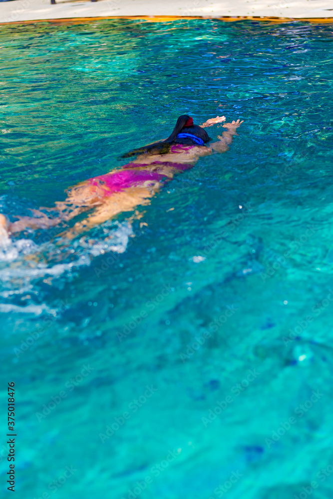 Woman traveler in bikini is swimming in pool