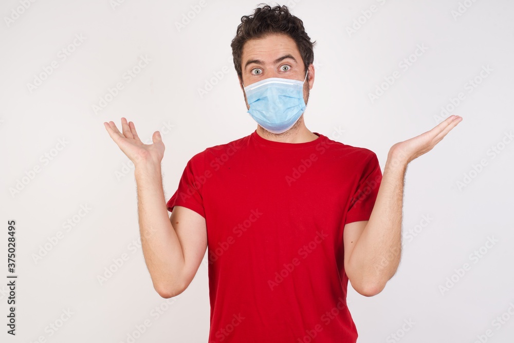 Young caucasian man with short hair wearing medical mask standing over isolated white wall celebrating crazy and amazed for success with arms raised and open eyes screaming excited. Winner concept Young caucasian man with short hair wearing medical mask standing over isolated white wall celebrating crazy and amazed for success with arms raised and open eyes screaming excited. Winner concept