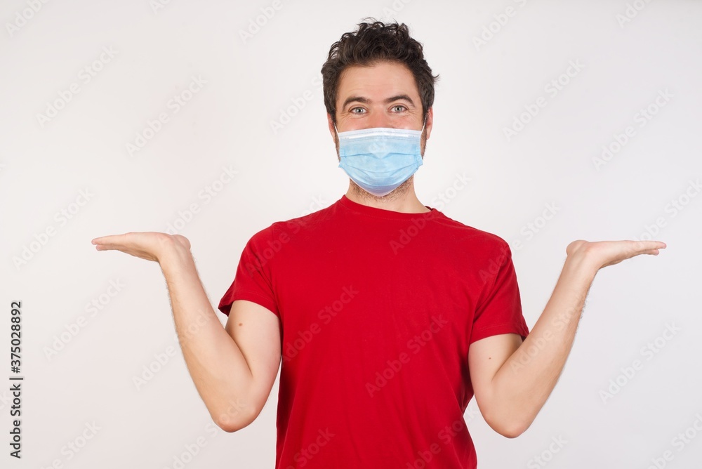 Young caucasian man with short hair wearing medical mask standing over isolated white background holding two palms copy space Young caucasian man with short hair wearing medical mask standing over isolated white background holding two palms copy space