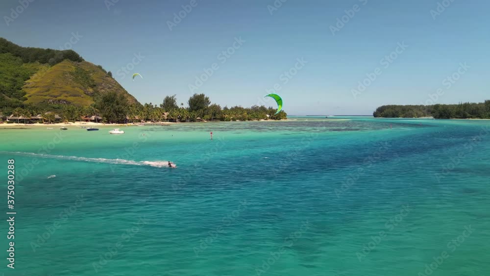 Drone aerial shot 4k. kiteboarding in turquoise crystal clear water blue lagoon of Moorea island Tahiti. French Polynesia adventure travel. Kitesurfing action sport. Drone aerial shot 4k. kiteboarding in turquoise crystal clear water blue lagoon of Moorea island Tahiti. French Polynesia adventure travel. Kitesurfing action sport.