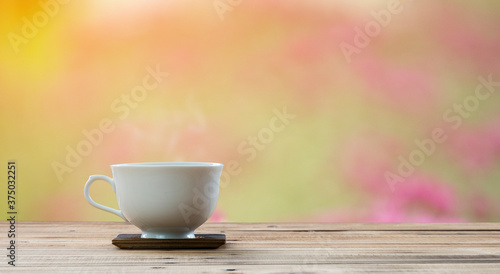 coffee cup on wooden table with flower background