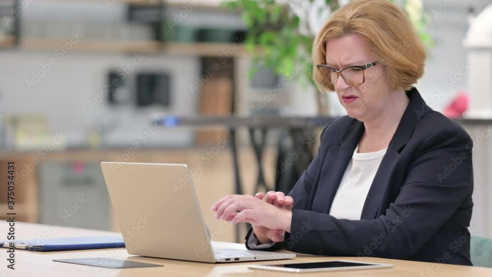 Old Businesswoman with Laptop having Wrist Pain in Office Old Businesswoman with Laptop having Wrist Pain in Office