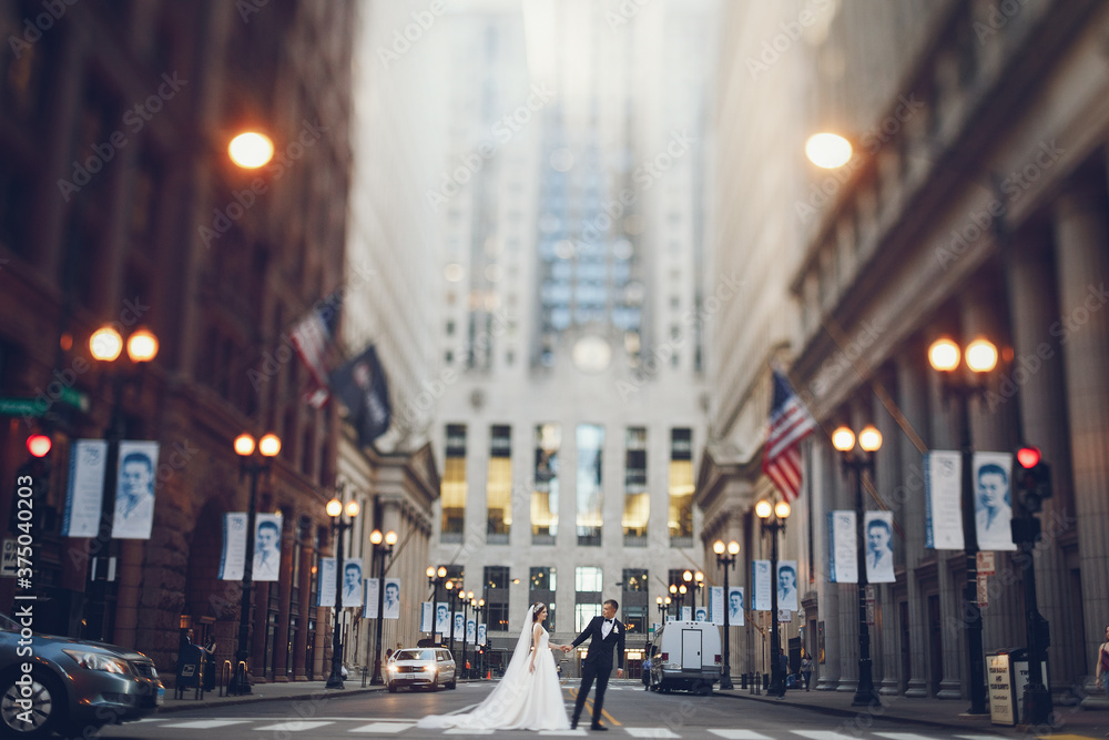 Elegant bride in a white dress and veil. Handsome groom in a blue suit. Couple in a big city