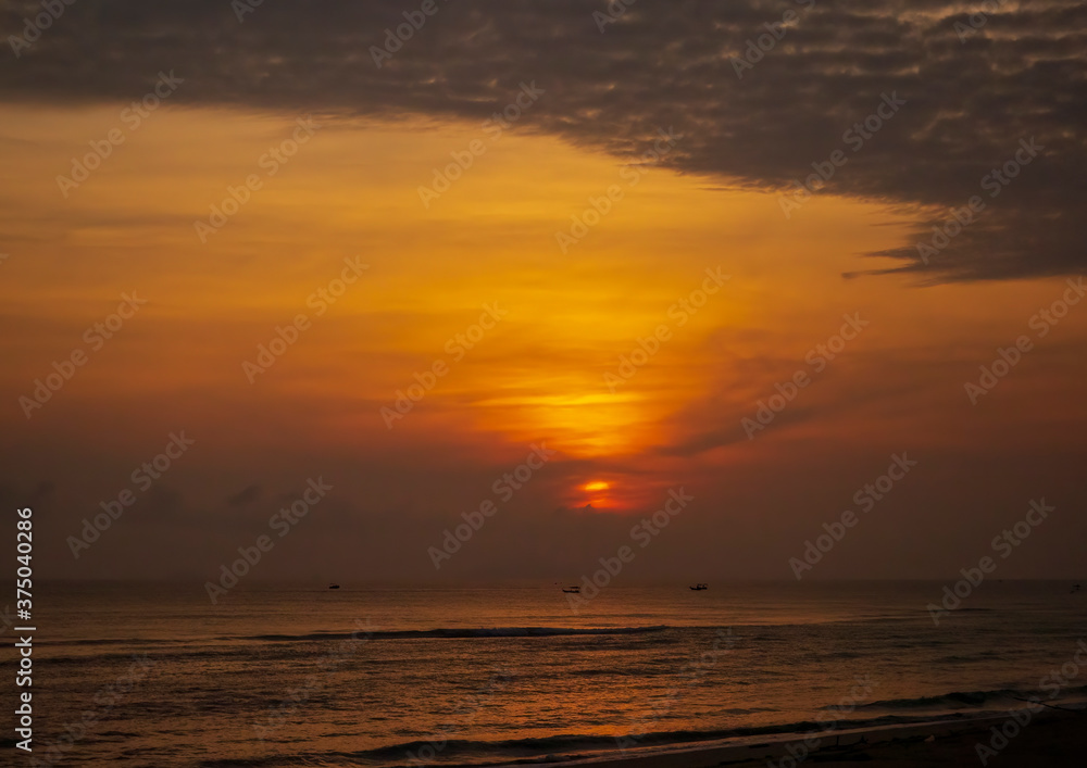 Ocean at dawn with the sun's golden orb against the background glow of sunrise.