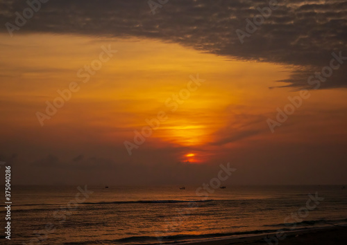 Ocean at dawn with the sun s golden orb against the background glow of sunrise.