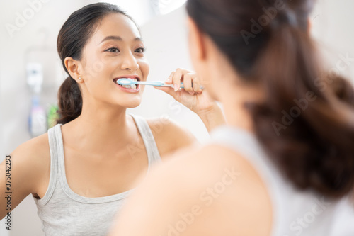 Beautiful female brushing teeth in the bathroom
