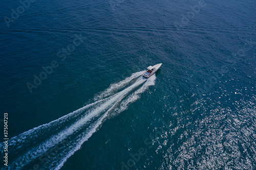 Drone view of a yacht sailing across the blue clear waters. Top view of a white yacht sailing in the blue sea. Aerial view luxury motor yacht. © Berg