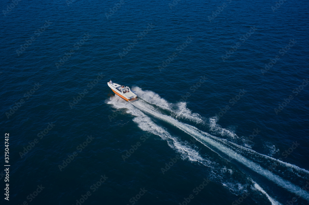 Top view of a white boat sailing in the blue sea. A boat with a motor on blue water. Aerial view luxury motor boat.  Top view of the boat.