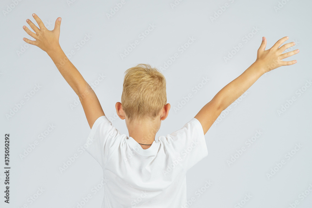 A portrait of a schoolboy who turned away from the camera and held his hands up. Isolated background. A portrait of a schoolboy who turned away from the camera and held his hands up. Isolated background.