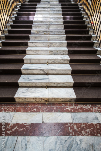 Old marble stairs with brown carpet