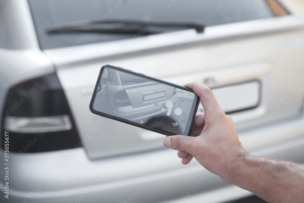 Man taking photo of a car on his phone.