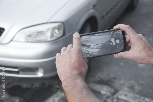 Man taking photo of a car on his phone.