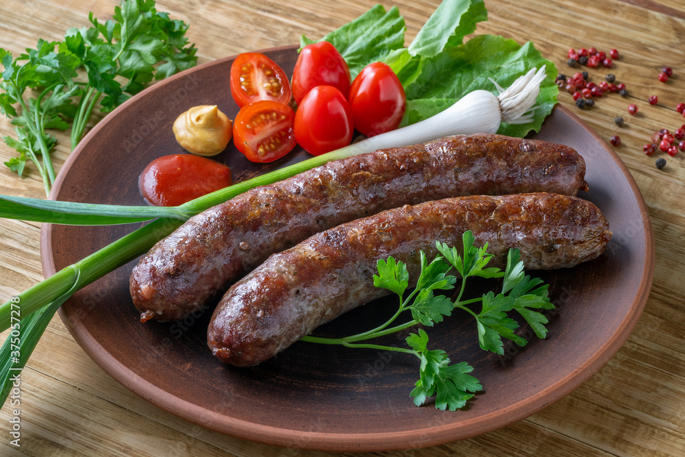 Food poster, restaurant setting - a portion of grilled sausages with tomatoes and herbs, ketchup, mustard. On a rustic table. Food poster, restaurant setting - a portion of grilled sausages with tomatoes and herbs, ketchup, mustard. On a rustic table.
