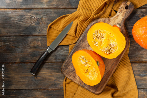 Hokkaido Pumpkins. Sliced pumpkin on a Board on a brown wooden table. Pumpkins close-up. The concept of the fall harvest. Top view with space for text