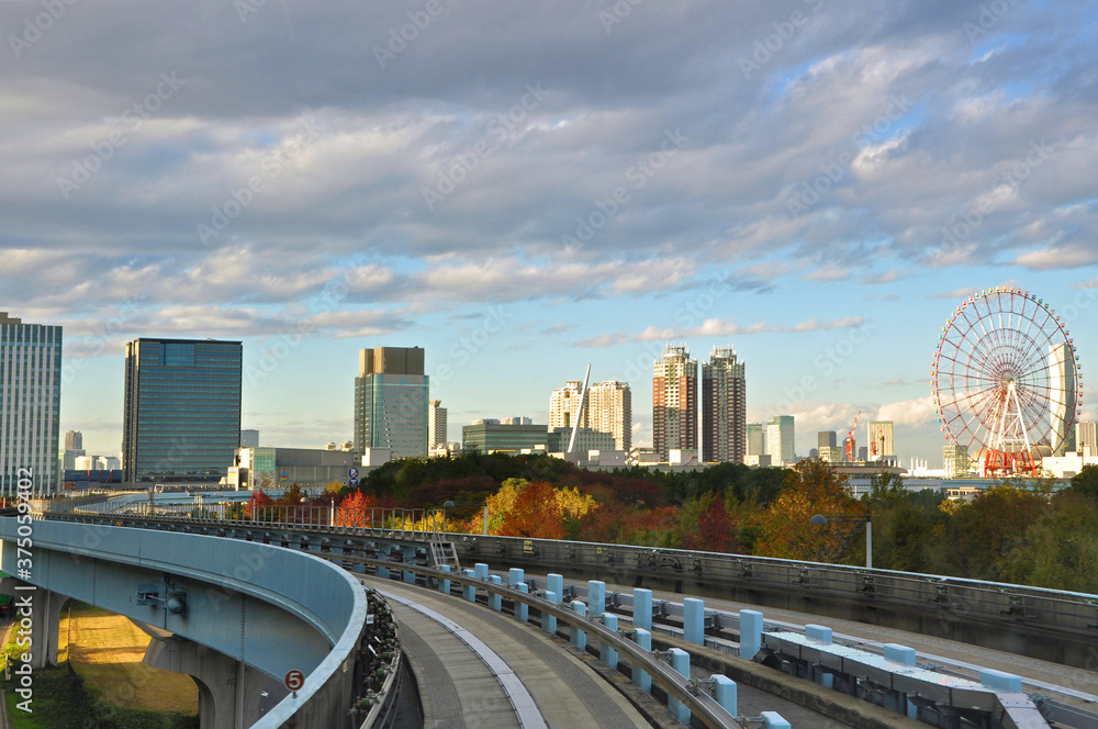 Riding on monorail train to Odaiba Island among modern and Futuristic architecture of Tokyo city and autumn color trees