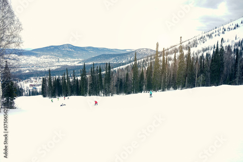 Nice mountains view at sunny day with skiers and snowboarders under blue sky with sun light at winter time.