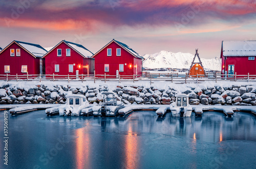 Typical red wooden houses on the shore of Offersoystraumen fjord. Stunning winter sunrise on Vestvagoy island. Colorful mornig view of Lofoten Islands, Norway, Europe.  Life over polar circle. photo