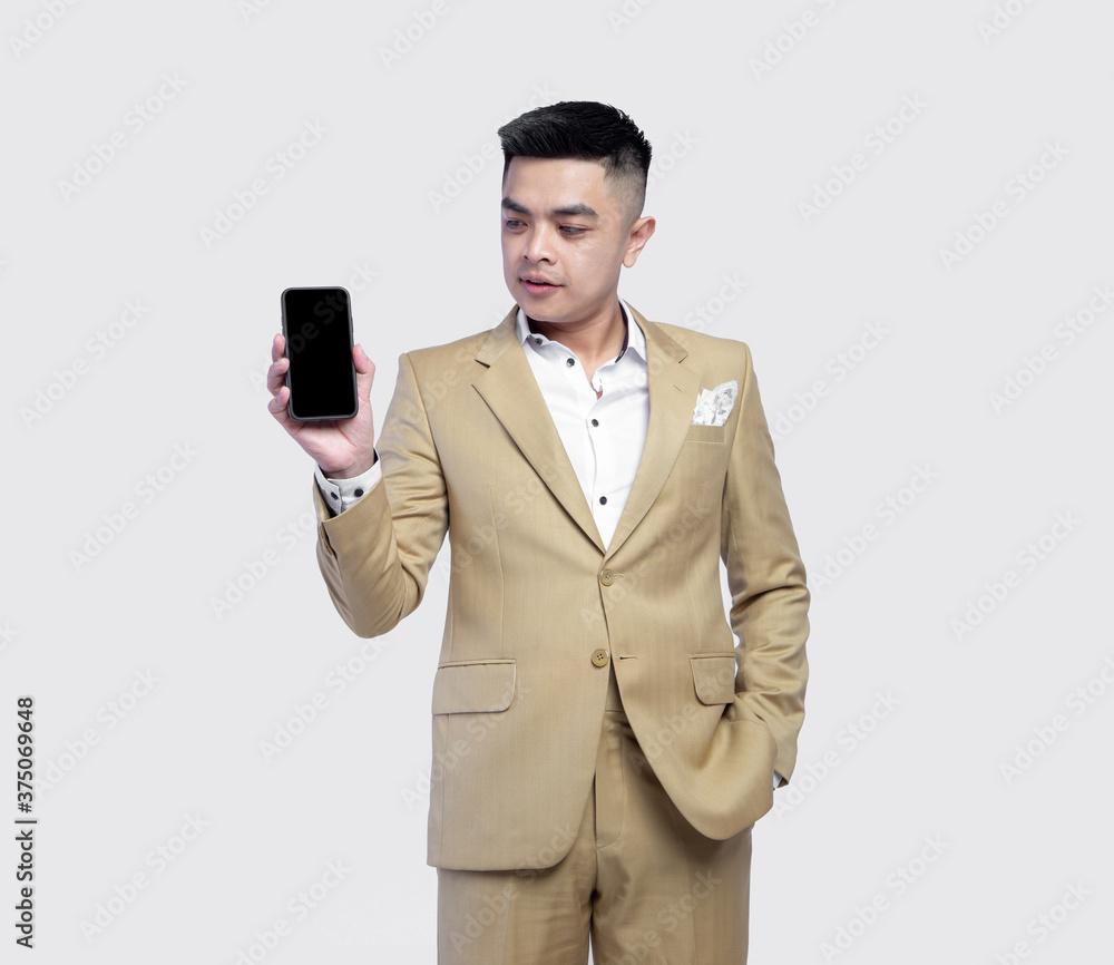Young handsome business man wearing suit holding mobile phone isolated on background Young handsome business man wearing suit holding mobile phone isolated on background
