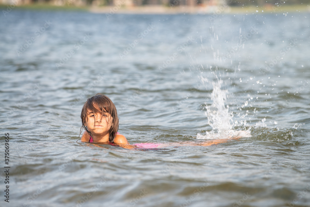 Young girl learning to swim in a mountain lake