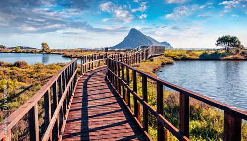 Fototapeta Naklejka Na Ścianę i Meble -  Wonderful summer view of Spiaggia di Porto Taverna beach with wooden footpath bridge. Amazing morning scene of Sardinia island, Italy, Europe. Picturesque Mediterranean seascape.