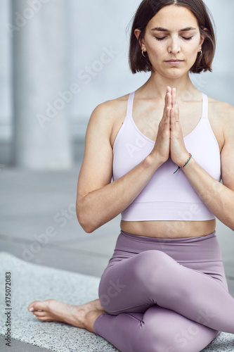 Frau/Mädchen in Pastell gekleidet macht Outdoor Yoga Übungen/Sonnegruß in moderner Beton Architektur. Urbanes Leben. 