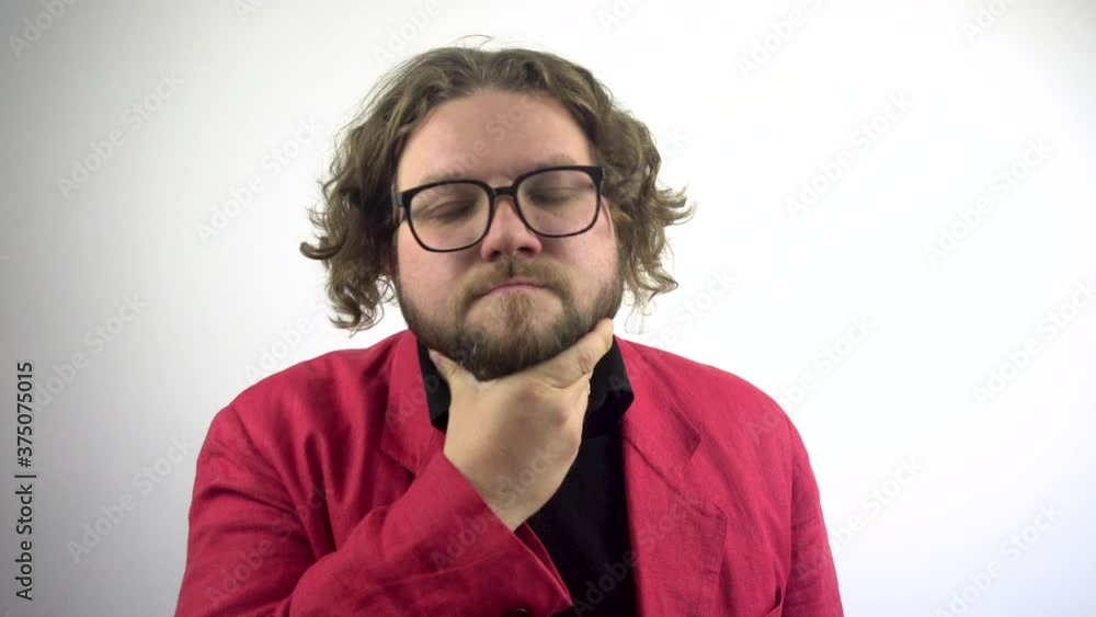 A young man in a red business suit looks at himself in the mirror and straightens his hair.The young man straightens his hair and glasses, looking in the mirror. White background.4k. A young man in a red business suit looks at himself in the mirror and straightens his hair.The young man straightens his hair and glasses, looking in the mirror. White background.4k.
