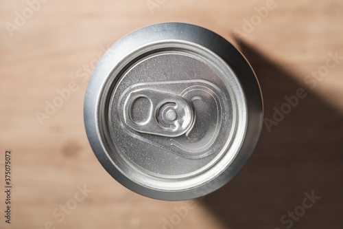 Closed shiny aluminum can stands on a wooden table