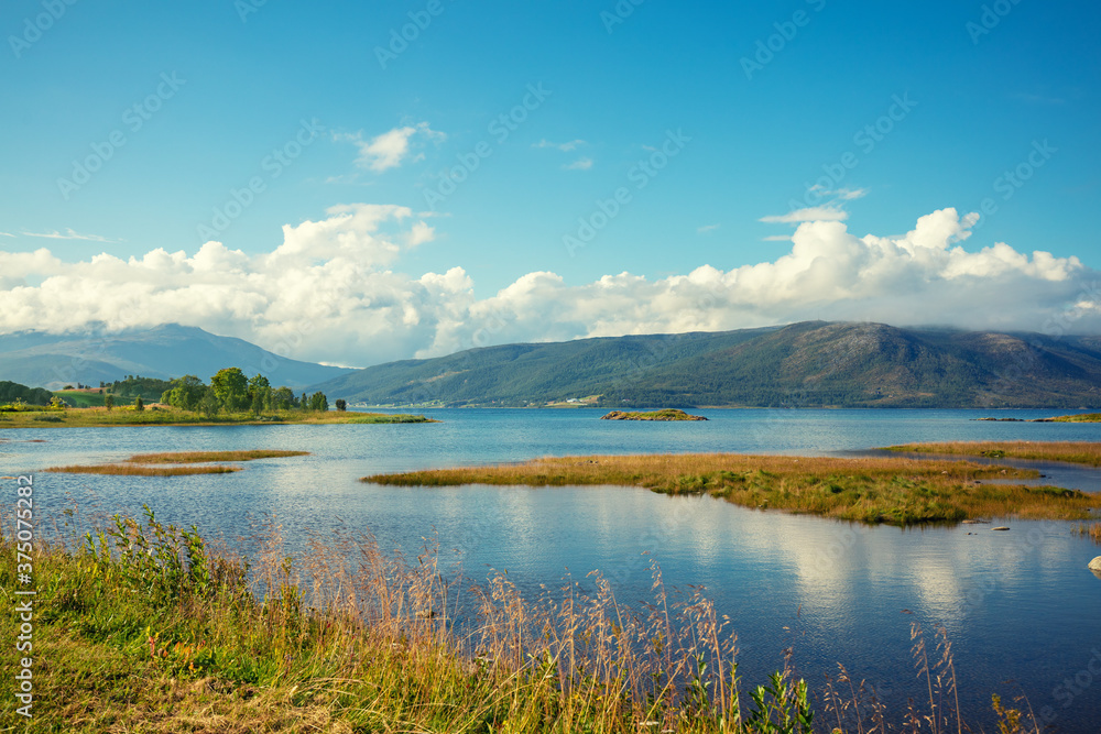 View of the fjord on a summer sunny day. Seashore with beautiful cloudy sky. Beautiful nature of Norway