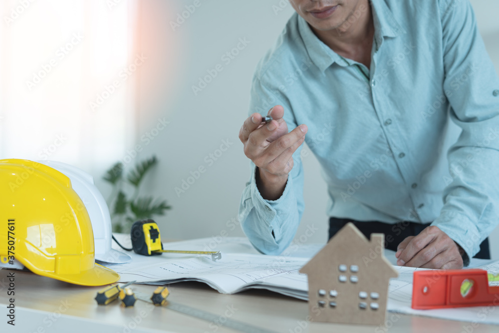 Male engineers standing at the desk are ready to write and review the blueprints used to build commercial buildings for joint ventures. Concept of engineer, architect Male engineers standing at the desk are ready to write and review the blueprints used to build commercial buildings for joint ventures. Concept of engineer, architect