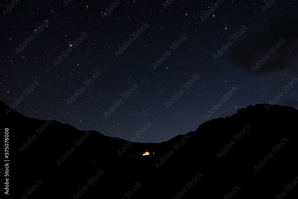 Starry sky in the mountains. Tourist tent in the mountains under the starry sky.