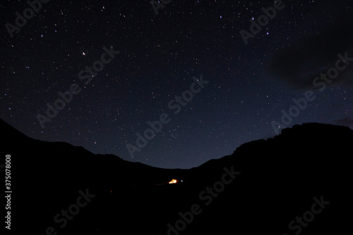 Starry sky in the mountains. Tourist tent in the mountains under the starry sky.