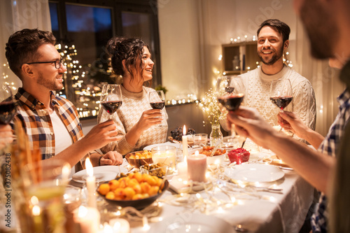 holidays  celebration and people concept - happy friends having christmas dinner at home drinking non-alcoholic red wine