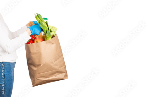 Woman holds a paper bag filled with groceries such as fruits, vegetables, milk, yogurt, eggs isolated on white.