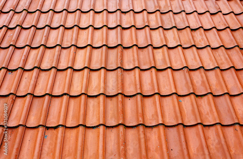 Old roof tiles on the roof of an house as seamless pattern. Red tiles roof texture architecture background  detail of house close up.
