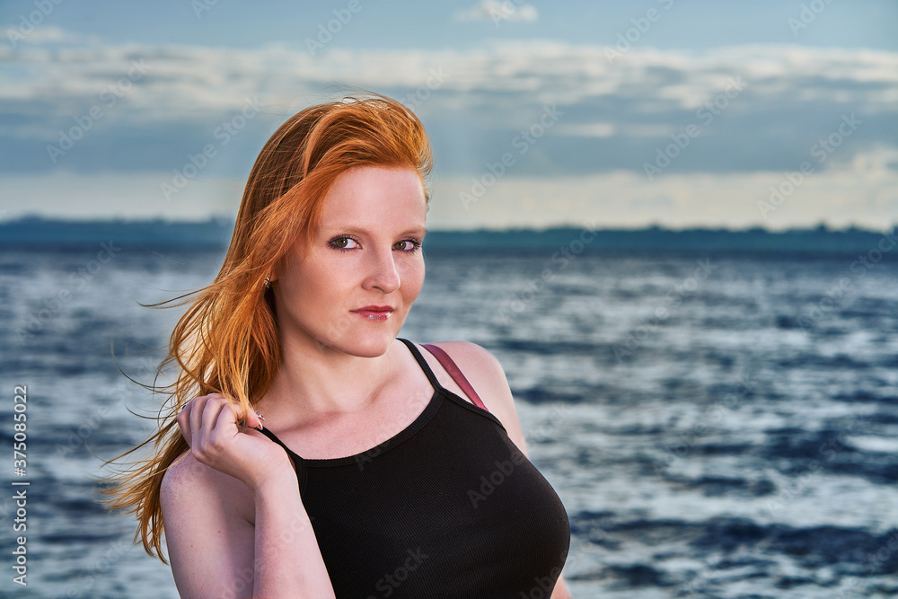 Portrait of a red-haired girl standing by the sea. Portrait of a red-haired girl standing by the sea.