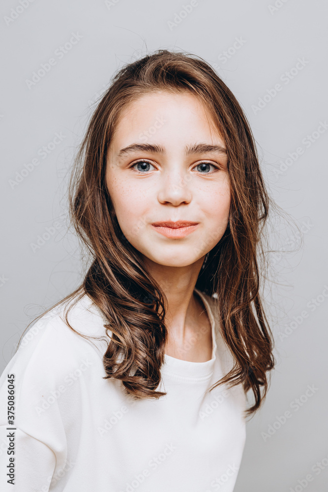 little pretty girl with expressive facial features posing for a photo on a gray background little pretty girl with expressive facial features posing for a photo on a gray background
