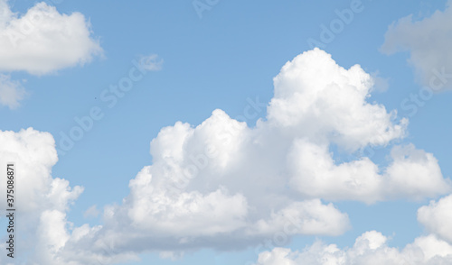 White cumulus clouds and cirrus clouds against the blue sky.