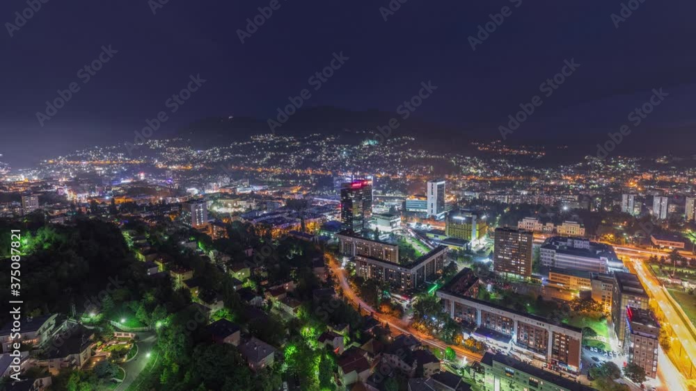 Aerial view of the southern part of Sarajevo city day to night transition timelapse. Skyline with skyscrapers and mountains from tallest tower viewpoint after sunset. Bosnia and Herzegovina, Southeast Aerial view of the southern part of Sarajevo city day to night transition timelapse. Skyline with skyscrapers and mountains from tallest tower viewpoint after sunset. Bosnia and Herzegovina, Southeast