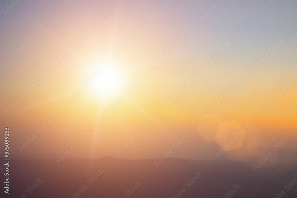 Fototapeta premium Natural background blurring warm colors and bright sunlight. Bokeh or Christmas background Green Energy at sky sunny color orange light patterns plain abstract flare evening clouds blur.