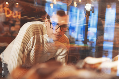 Handsome man choosing sweets and cakes in cafe. Attractive man buying desserts at the coffee shop. Male customer choosing cookies at confectionery store