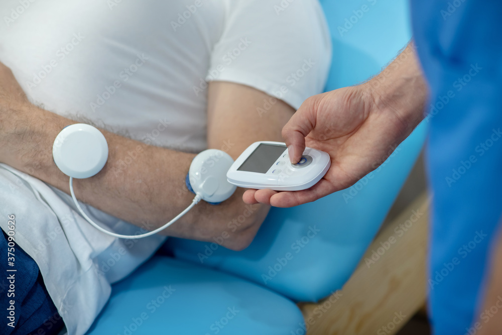 Close-up of patient lying on couch, having his muscles stimulated Close-up of patient lying on couch, having his muscles stimulated