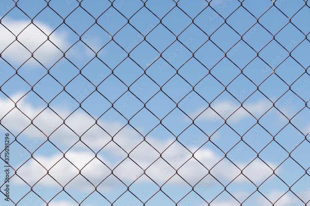 Metal grid against the blue sky with white clouds. Metal grid against the blue sky with white clouds.