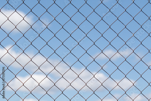 Metal grid against the blue sky with white clouds.