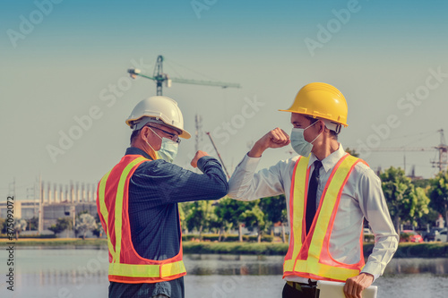 Engineers saluting each other by touching elbows,Two business people shake hand no touch outdoor on site construction