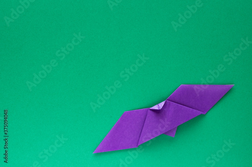 purple origami bat on green background