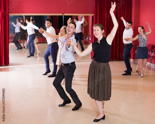 Cheerful group people dancing lindy hop in pairs in dance hall