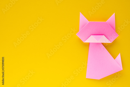 pink origami cat on yellow background