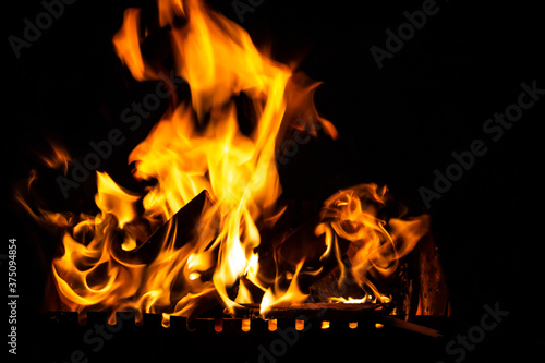 Fire on a dark background. Fire from firewood close up. Flaming burning sparks close-up, fire patterns. Red and orange Infernal glow of fire in the dark.