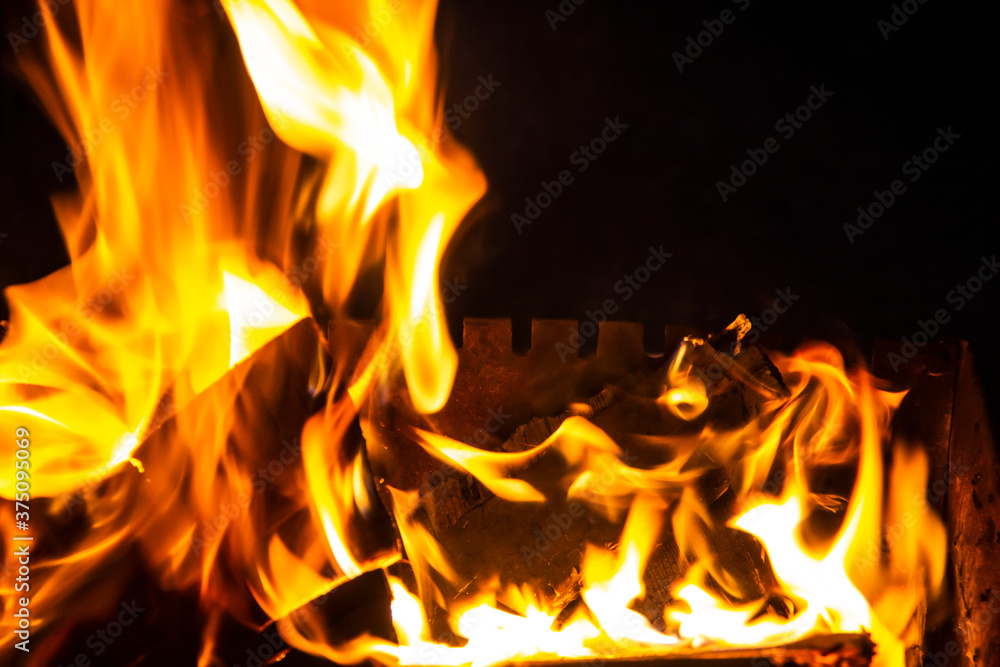 Fire on a dark background. Fire from firewood close up. Flaming burning sparks close-up, fire patterns. Red and orange Infernal glow of fire in the dark. Fire on a dark background. Fire from firewood close up. Flaming burning sparks close-up, fire patterns. Red and orange Infernal glow of fire in the dark.