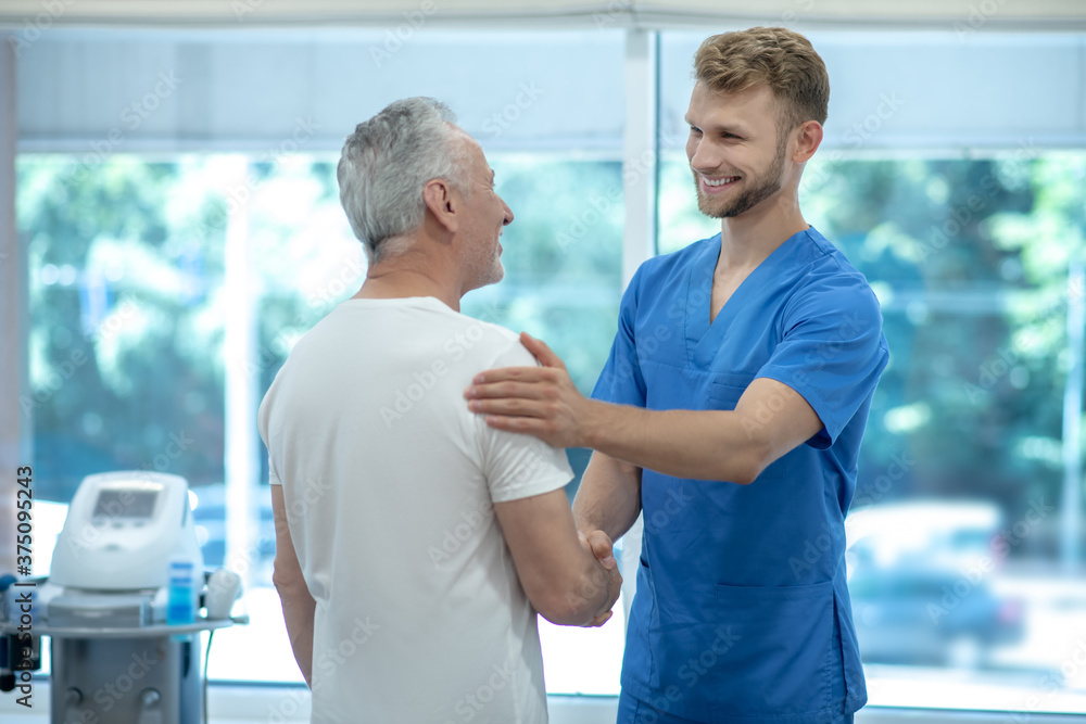 Obraz premium Young doctor shaking hand to elderly patient